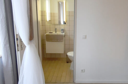 Maison Fasson Ferienwohnung 1 - Schlafzimmer mit Himmelbett, Blick in die Toilette