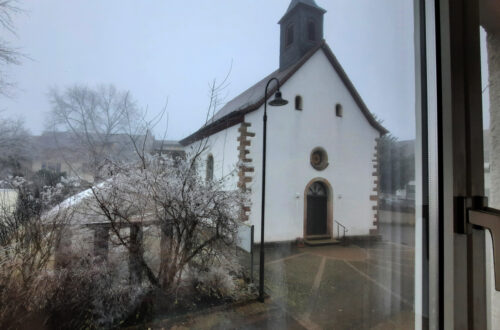 Maison Fasson Ferienwohnung 1 Wohnzimmer, Blick aus dem Fenster auf die gegenüberliegende Kirche