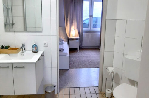 Maison Fasson Ferienwohnung 1 Duschbad Waschtisch, Toilette, Blick ins Schlafzimmer